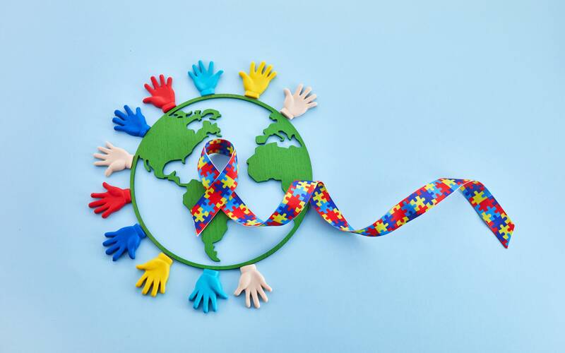 Autism awareness colors with hands and the globe
