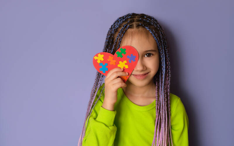 girl standing with autism awarness heart