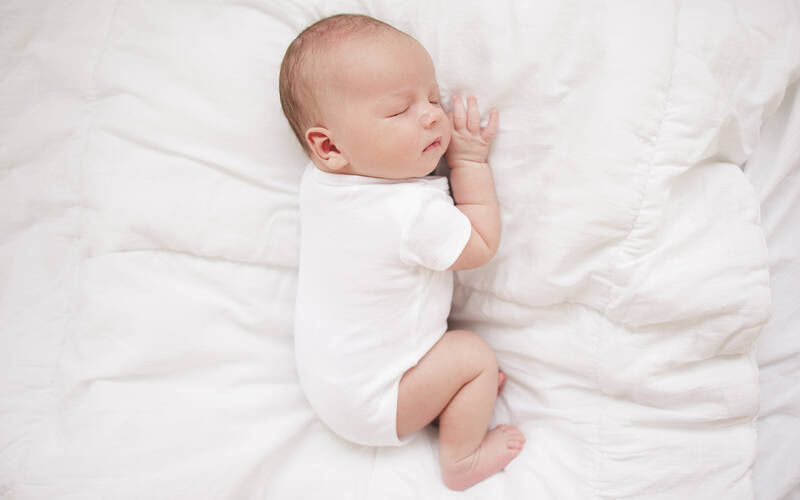 Newborn sleeping on bed