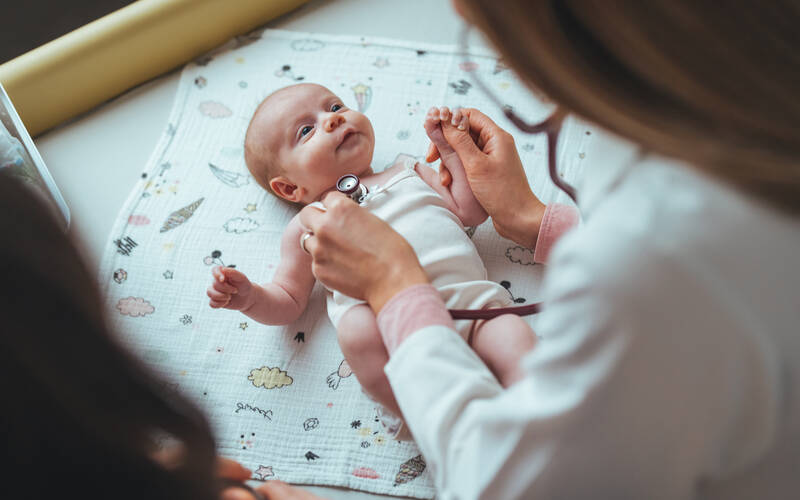 Baby at doctor appointment doctor holding stethoscope to newborn chest