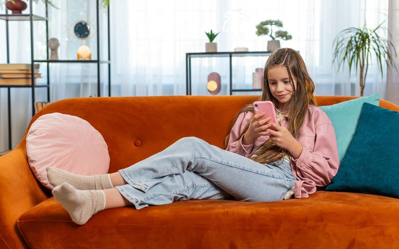 teen sitting on couch looking at phone