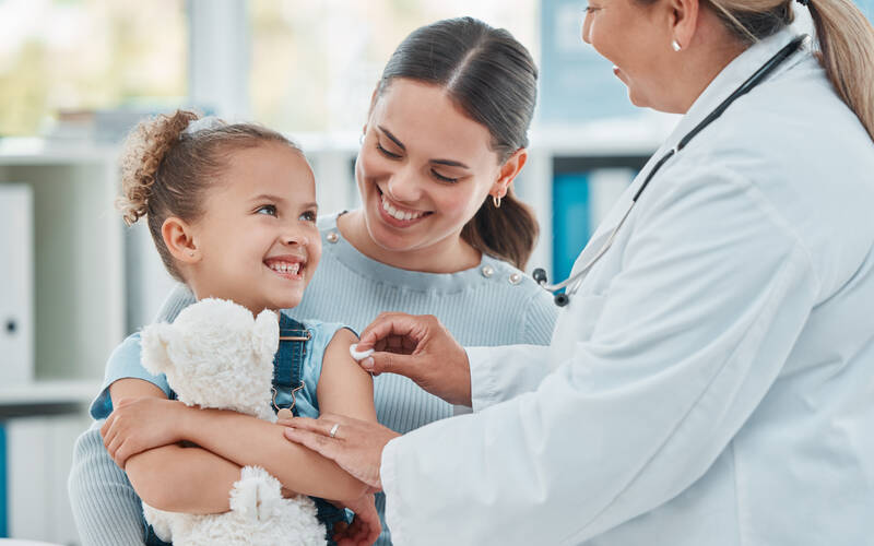 girl with mom smiling after vaccine