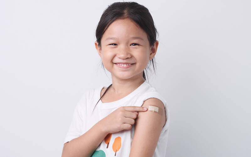 girl smiling pointing to band aid on arm