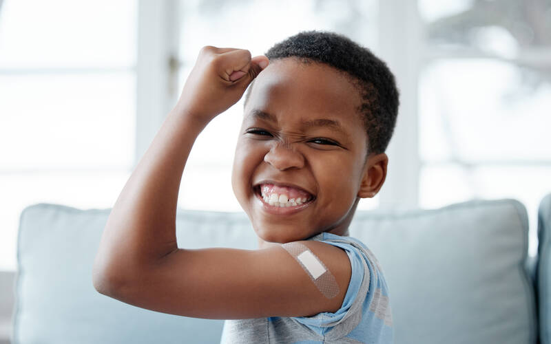 boy holding up arm muscle with bandaid