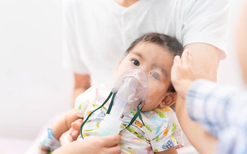 baby sitting with breathing mask