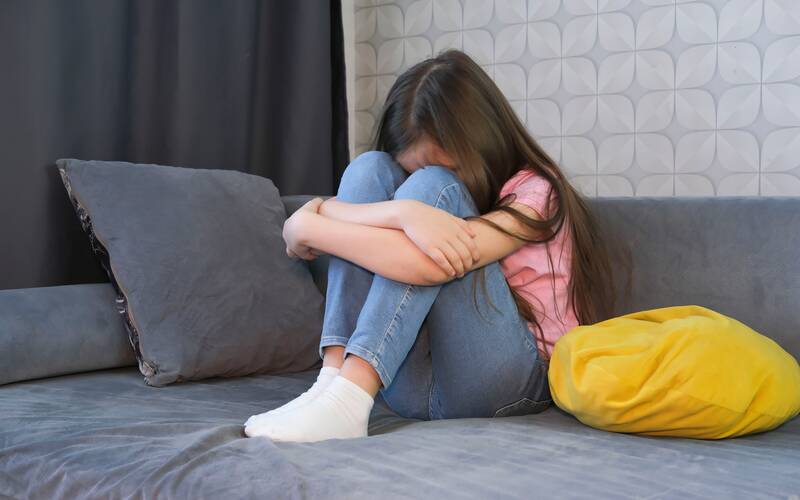Kid upset on couch curled up