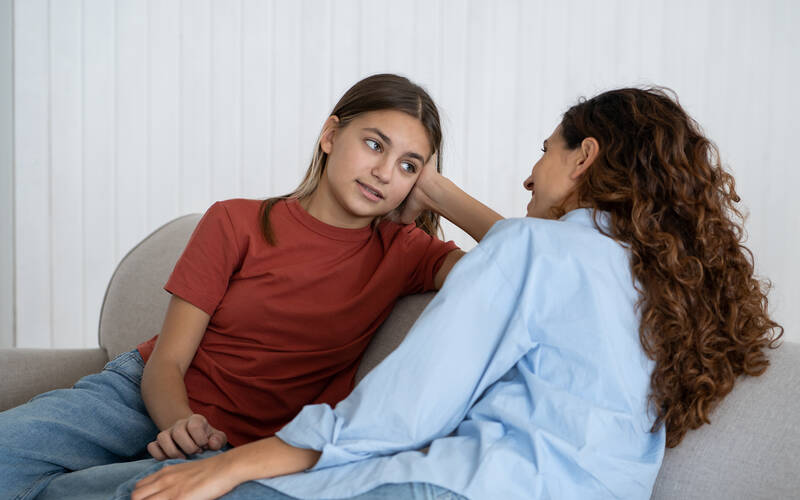 teen talking to adult on couch
