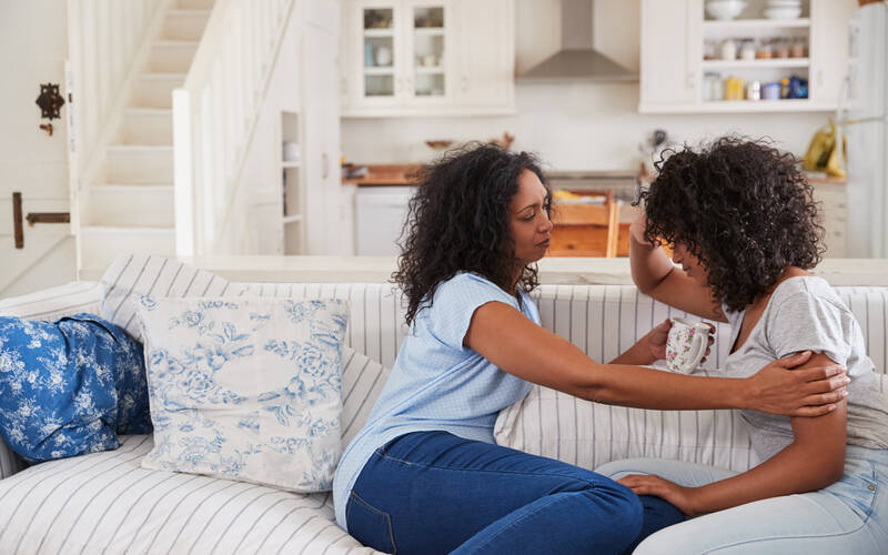 two people sitting on couch comforting
