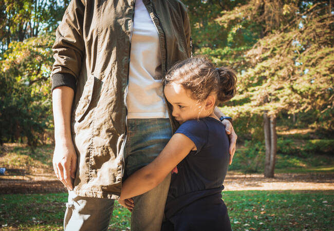 girl holidng onto dads leg