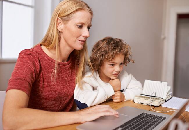 mom and child sitting at a table on a computer