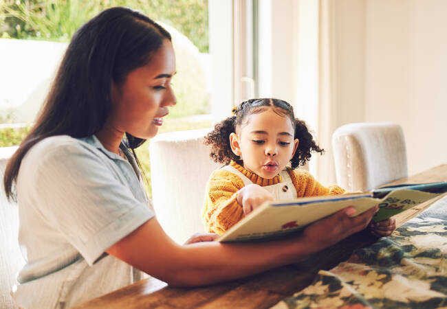 mom and daughter reading at table