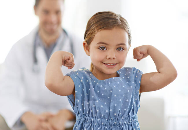 young girl showing arm muscles at doctor