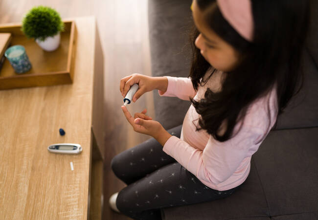 girl sitting at desk testing blood sugar