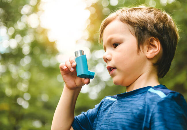 young boy outside holding inhaler