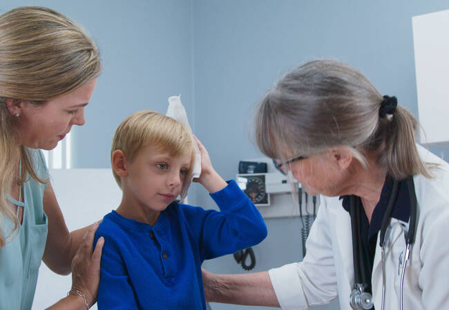 kid at doctor holding head