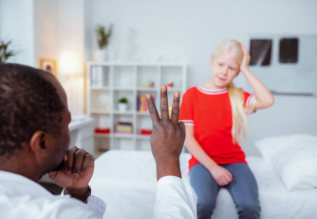 Doctor holding up fingers to girl with head injury