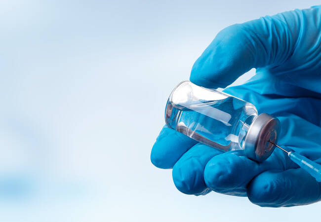 hand with glove on using vaccine