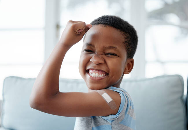 boy holding up arm muscle with bandaid