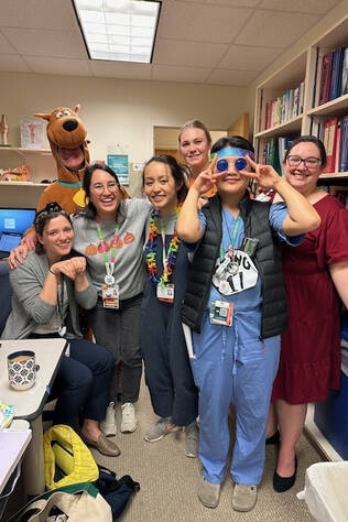 Pediatric residents laughing and posing with someone dressed in a Scooby-Doo costume