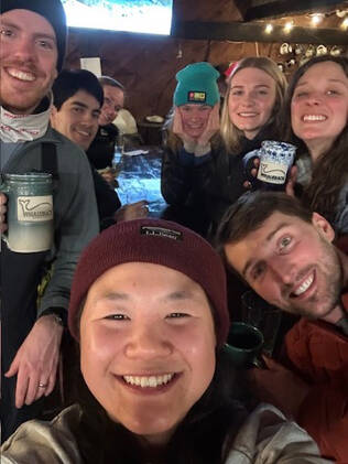 Pediatric residents in the Whaleback Mountain ski lodge, wearing ski hats and drinking warm drinks in Whaleback mugs