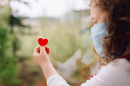 Girl with a paper heart in front of window
