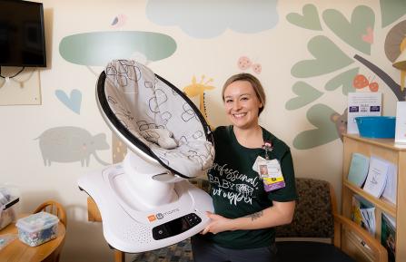 Nurse Victoria Hastings poses holding a MamaRoo baby swing.