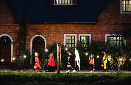 Image of children trick-or-treating in Halloween costumes at night