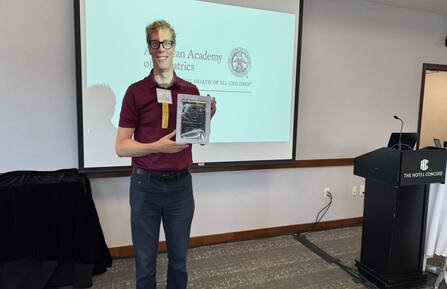 Erik Shessler stands with award