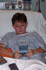 Boy playing with a Game Boy in a hospital bed