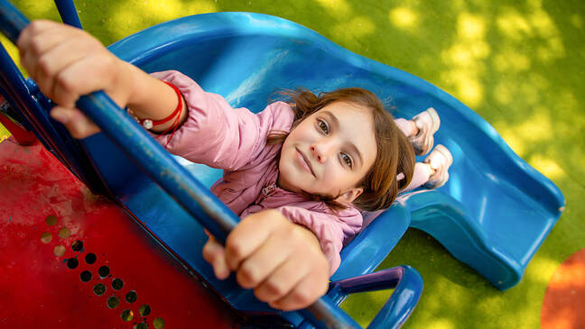 Girl outside hanging onto a slide