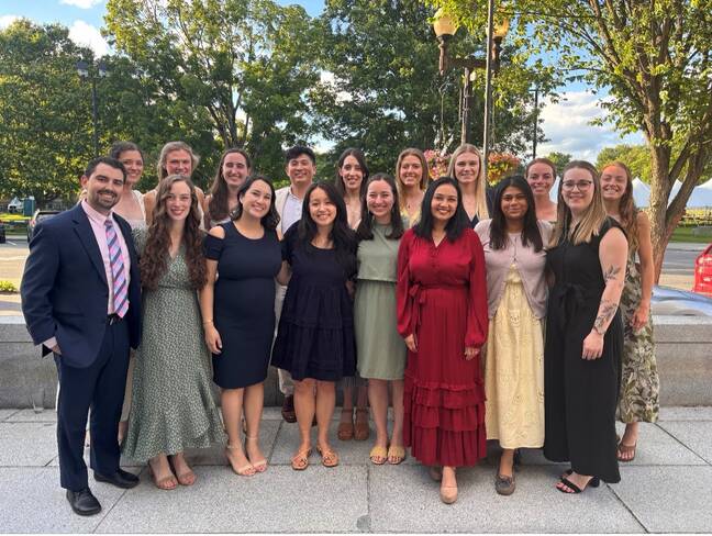 A group of nicely dressed people pose for a photo outdoors