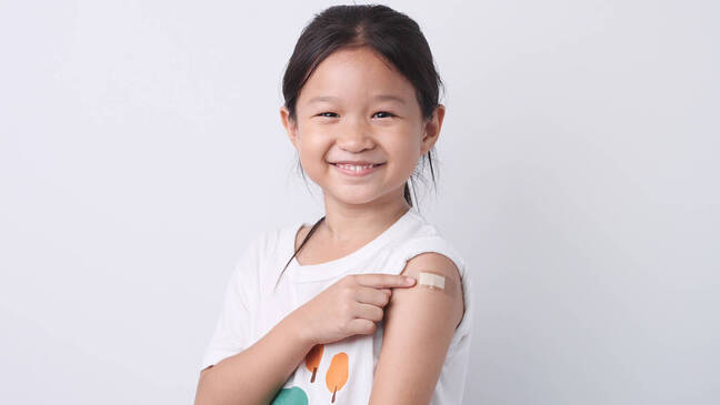 Young girl with Band-Aid on arm, pointing to it.