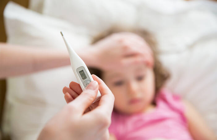 Sick child with mom taking the temperature