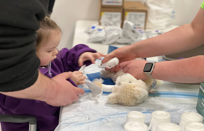Child putting gauze on teddy bear